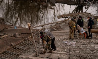 Soldados ajudam moradores a atravessar ponte destruída